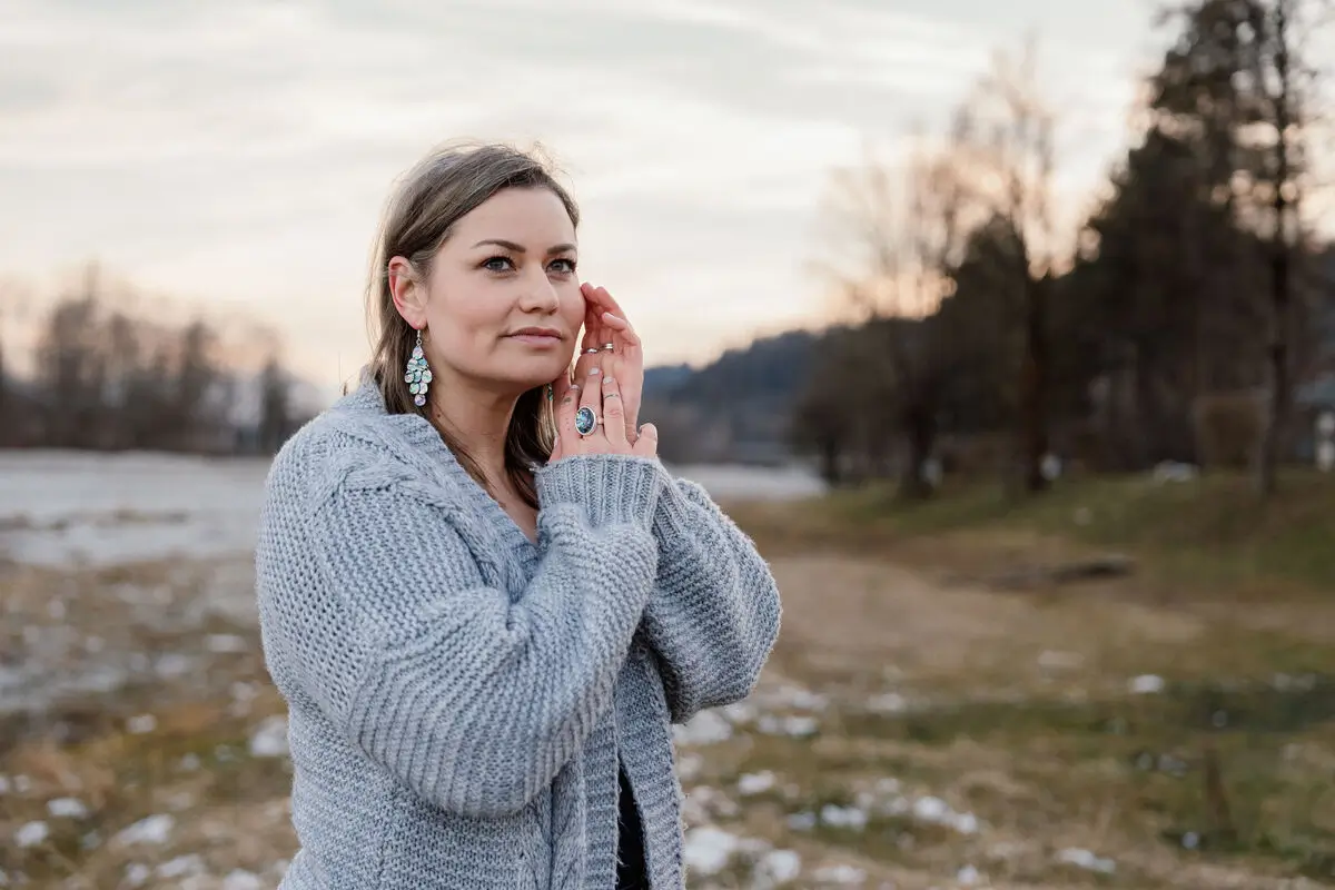 Jennifer Heng steht an einem Bachufer am Waldrand und schaut in die Ferne hinter der Kamera
